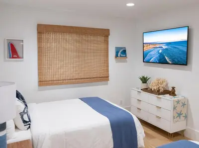 a bedroom with a bed and a tv on the wall at Luxury 2BR Steps to Beach & Pier with AC plus Garage Parking in Newport Beach
