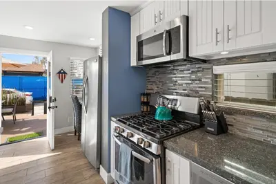 a kitchen with white cabinets and a stove top oven at Stunning Beach Home - large patio, parking, ac & dog friendly! in San Diego