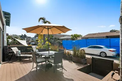 a table and chairs with an umbrella on a patio at Stunning Beach Home - large patio, parking, ac & dog friendly! in San Diego