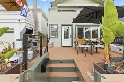 a patio with a table and chairs and an umbrella at Stunning Beach Home - large patio, parking, ac & dog friendly! in San Diego