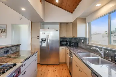 a kitchen with a stainless steel refrigerator and a window at Stunning South Mission Beach Home - AC, Private Patio, Grill and Garage! in San Diego