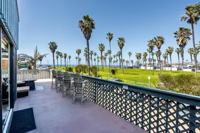 a balcony with tables and chairs and palm trees at Belmont Ocean Views - Massive Private Deck, Grill & Parking in San Diego