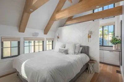 a bedroom with a large bed with white walls and windows at Neptune Experience in Encinitas