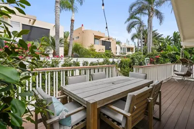 a wooden table and chairs on a deck with palm trees at Neptune Experience in Encinitas