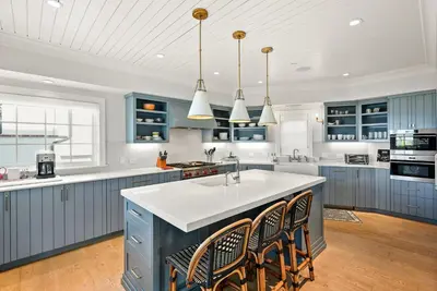 a kitchen with blue cabinets and a kitchen island with chairs at Coastal La Jolla Luxury w AC, Patios, & Massive Ocean Views! in San Diego