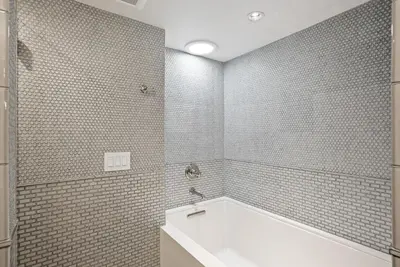 a bathroom with a tub and a white tiled wall at Cabrillo Villa - Massive 7br La Jolla Estate in San Diego