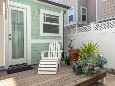 a white rocking chair on a porch with plants at Stunning beach home - steps2sand, AC, Large Patio and Fast Wifi! in San Diego
