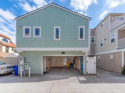 a large green house with a garage in a driveway at Stunning beach home - steps2sand, AC, Large Patio and Fast Wifi! in San Diego