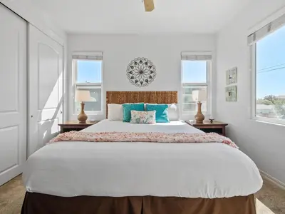 a bedroom with a large bed with two windows at Pacific Beach Paradise - Near the Beach w AC, Garage, Fast Wifi & Private Patio! in San Diego