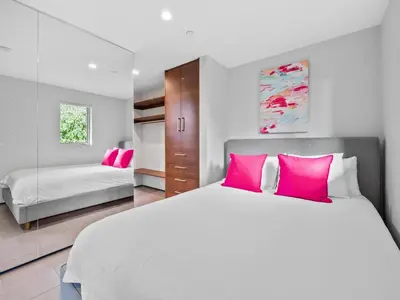 a bedroom with a large white bed with pink pillows at Luxury Coastal Home - Pool, Spa, AC, & Ocean Views in Solana Beach