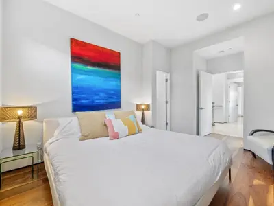 a bedroom with a white bed and a painting on the wall at Luxury Coastal Home - Pool, Spa, AC, & Ocean Views in Solana Beach
