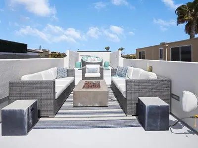 a patio with wicker furniture and a table on a balcony at Haines Luxury Dream Home - Bay Views, Rooftop, Fire Pit & AC in San Diego