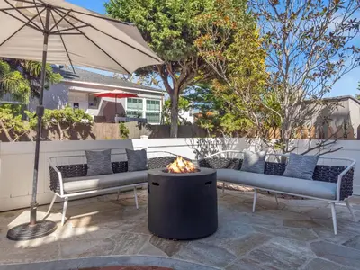 a fire pit with two benches and an umbrella at Kennebeck Oasis - Private Patio, Steps 2 Sand & AC in San Diego