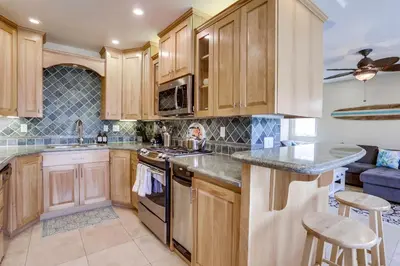 a kitchen with wooden cabinets and a stove top oven at Stunning Ocean View Home w Rooftop Terrace, Firepit, Fast Wifi, AC & Parking! in San Diego