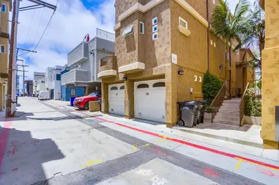 a street with garages on the side of a building at Stunning Ocean View Home w Rooftop Terrace, Firepit, Fast Wifi, AC & Parking! in San Diego