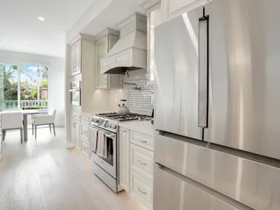 a kitchen with white cabinets and a stainless steel refrigerator at Coastal retreat near the beach w Panoramic Ocean Views, Rooftop Deck, & Firepit in San Diego