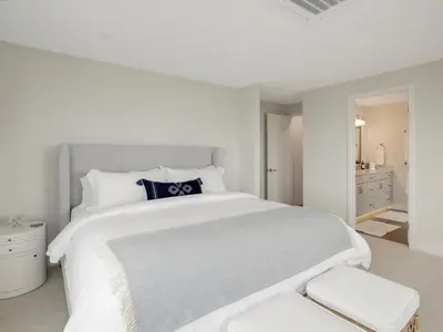 a white bedroom with a large white bed with a blue pillow at Coastal retreat near the beach w Panoramic Ocean Views, Rooftop Deck, & Firepit in San Diego