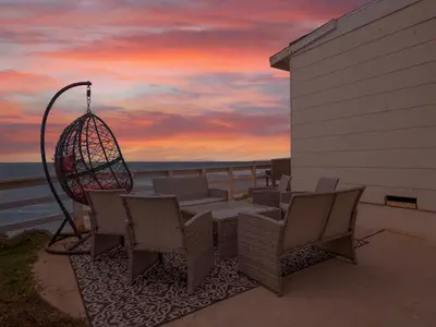 a patio with a table and chairs and a sunset at Oceanfront Paradise - Spa, Pet-Friendly, Fast Wifi, Parking & Dream Views in San Diego