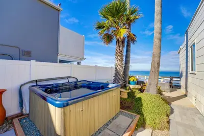 a hot tub in a backyard with palm trees and the ocean at Oceanfront Paradise - Spa, Pet-Friendly, Fast Wifi, Parking & Dream Views in San Diego