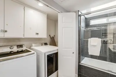 a kitchen with a washer and a glass shower at Massive Beach Home w Stunning Rooftop, Parking, Spa, AC & Bay Views! in San Diego
