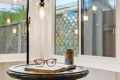 a table with a book and glasses and a can of beer at Massive Beach Home w Stunning Rooftop, Parking, Spa, AC & Bay Views! in San Diego