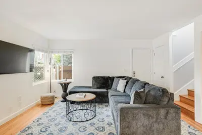 a living room with a couch and a table at Massive Beach Home w Stunning Rooftop, Parking, Spa, AC & Bay Views! in San Diego