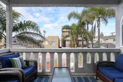 a balcony with chairs and a table and palm trees at Massive Beach Home w Stunning Rooftop, Parking, Spa, AC & Bay Views! in San Diego