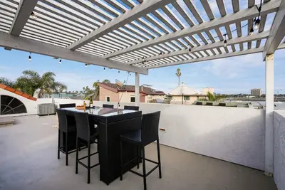a patio with a pergola and a table and chairs at Massive Beach Home w Stunning Rooftop, Parking, Spa, AC & Bay Views! in San Diego