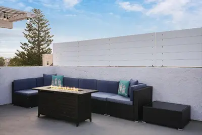 a patio with a blue couch and a table at Massive Beach Home w Stunning Rooftop, Parking, Spa, AC & Bay Views! in San Diego