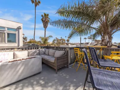 a patio with a couch and chairs and palm trees at Stunning Beach House- Rooftop Patio & Ocean Views in San Diego