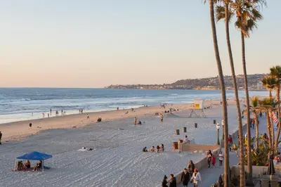 a group of people on a beach with the ocean at Oceanfront, two-level condo with stunning view, decks, fast WiFi & fireplace in San Diego