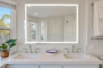 a white bathroom with two sinks and a mirror at Beautiful Beach Home - Ocean View, AC & Patio in San Diego