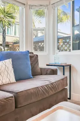 a living room with a couch and two windows at Beautiful Beach Home - Ocean View, AC & Patio in San Diego