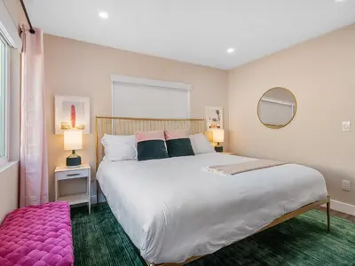 a bedroom with a large white bed and a pink rug at Classic Beach Bungalow - Parking, Private Patio & Pet Friendly! in San Diego