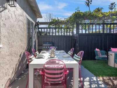 a white table with pink chairs on a patio at Classic Beach Bungalow - Parking, Private Patio & Pet Friendly! in San Diego