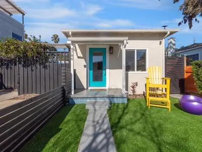 a house with a blue door and a yellow chair at Classic Beach Bungalow - Parking, Private Patio & Pet Friendly! in San Diego