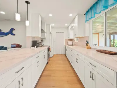 a large white kitchen with white cabinets and wood floors at Bay Park Garden Paradise - central Location, AC, Washer Dryer & Private yard! in San Diego