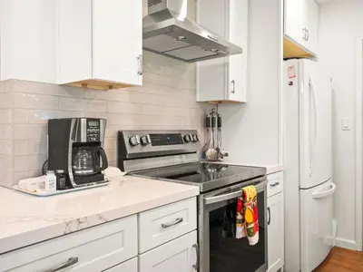 a kitchen with white cabinets and a black stove top oven at Bay Park Garden Paradise - central Location, AC, Washer Dryer & Private yard! in San Diego