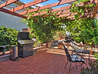 a patio with a grill and chairs under a wooden pergola at Bay Park Garden Paradise - central Location, AC, Washer Dryer & Private yard! in San Diego