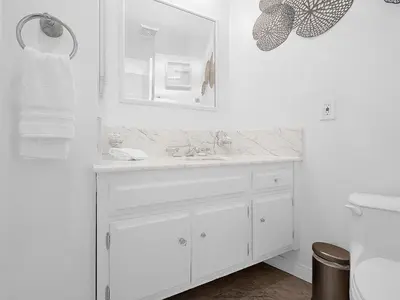 a white bathroom with a sink and a mirror at Sunset Cliffs Lookout - Ocean Front Luxury Condo in San Diego