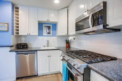 a kitchen with white cabinets and a stove top oven at Ormond Beach Oasis - Large Private Patio, WasherDryer, Pet Friendly & Steps2Sand! in San Diego