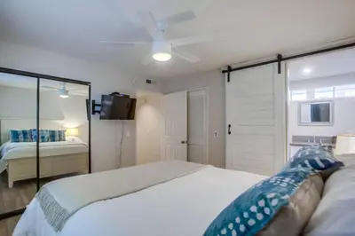 a bedroom with a white bed and a sliding glass door at Ormond Beach Oasis - Large Private Patio, WasherDryer, Pet Friendly & Steps2Sand! in San Diego