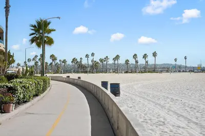 a sandy beach with palm trees and a sidewalk at Ocean View Paradise w Private Patio & Spa in San Diego