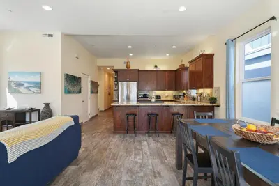 a kitchen with wooden cabinets and a blue couch in a room at Mission Paradise - Spa, Pet Friendly, Steps2Sand in San Diego