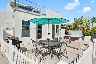 a table with chairs and an umbrella on a patio at Mission Paradise - Spa, Pet Friendly, Steps2Sand in San Diego
