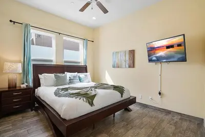 a bedroom with a bed and a tv on the wall at Mission Paradise - Spa, Pet Friendly, Steps2Sand in San Diego