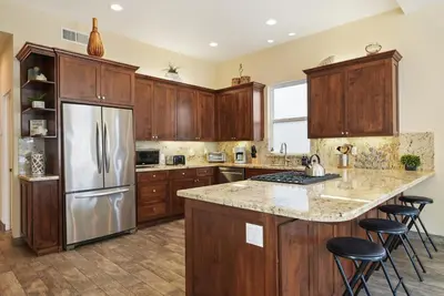 a kitchen with wooden cabinets and a stainless steel refrigerator at Mission Paradise - Spa, Pet Friendly, Steps2Sand in San Diego