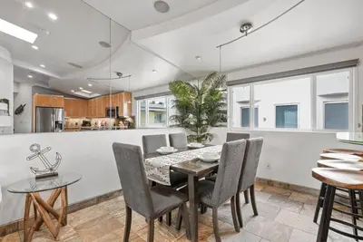 a kitchen and dining room with a table and chairs at Stunning Oceanfront Boardwalk Condo - Spa, Steps2Beach, Parking & Fast Wifi! in San Diego