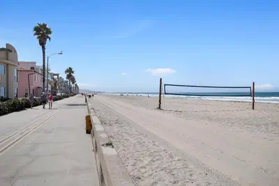 a sandy beach with a volleyball net on it at Stunning Oceanfront Boardwalk Condo - Spa, Steps2Beach, Parking & Fast Wifi! in San Diego