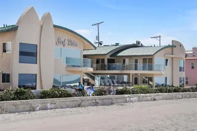 people riding bikes in front of a building on the beach at Stunning Oceanfront Boardwalk Condo - Spa, Steps2Beach, Parking & Fast Wifi! in San Diego